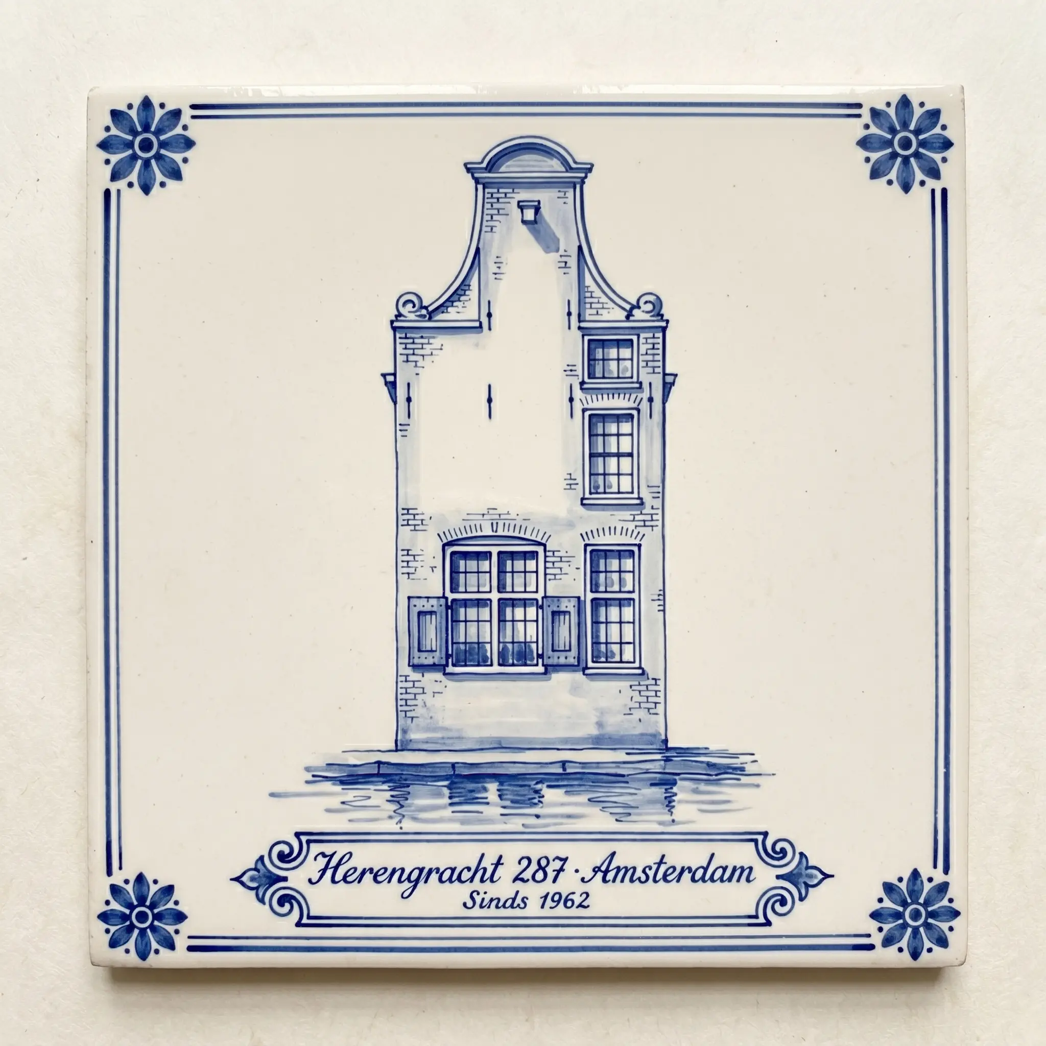 Delft Blue tile with a canal house facade and the address painted in cobalt Italianate calligraphy